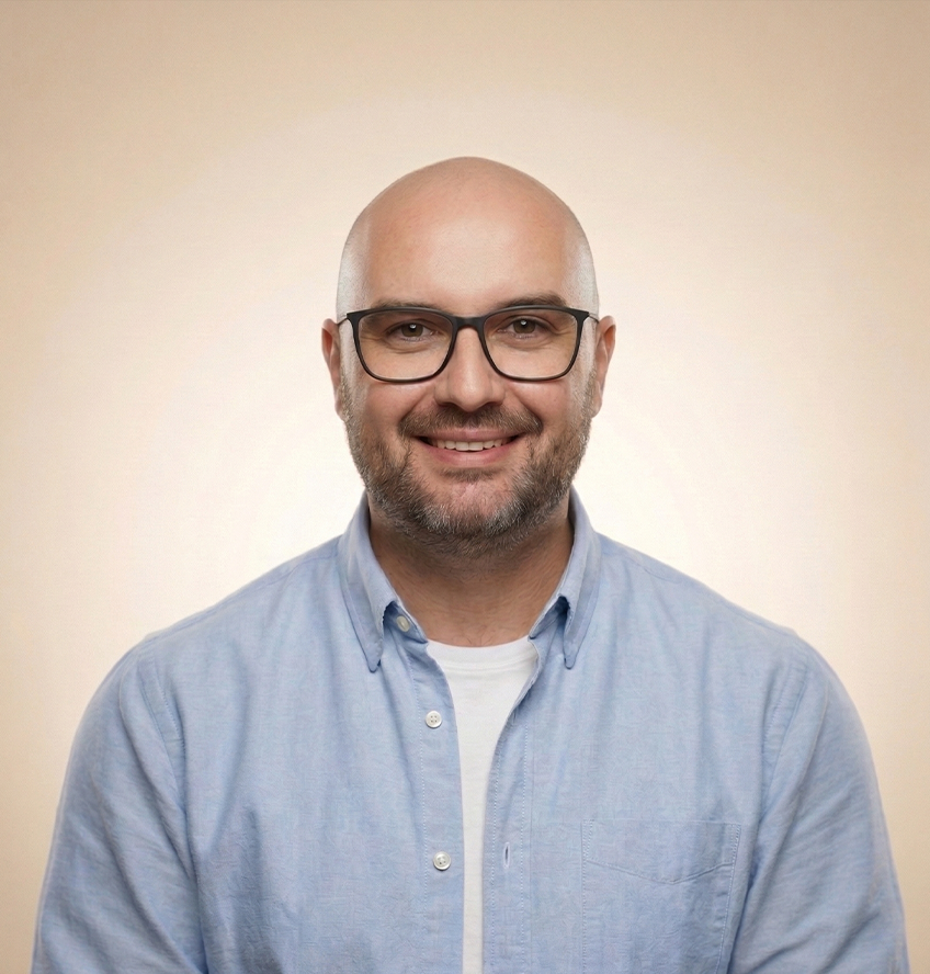 Portrait of a smiling professional man wearing glasses and a light blue shirt, used on a personal portfolio website.