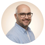 Portrait of a smiling professional man wearing glasses and a light blue shirt, used on a personal portfolio website.